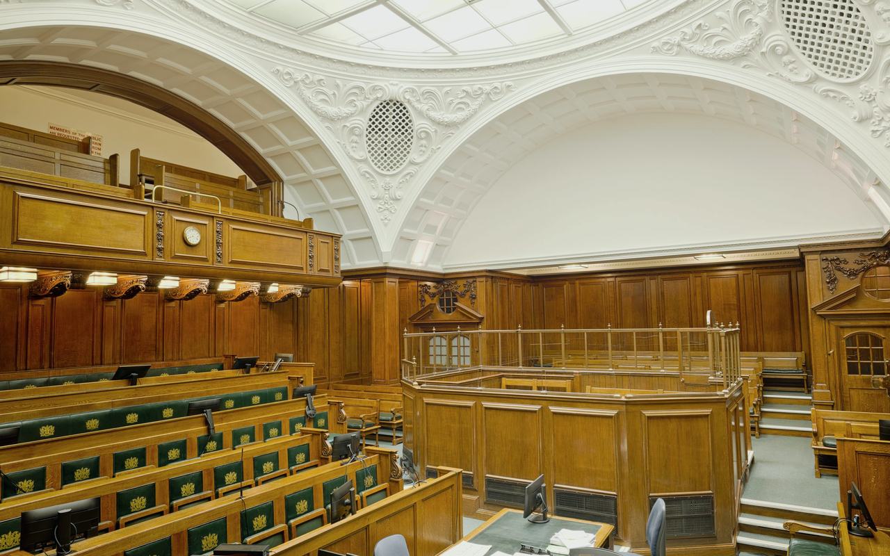 Interior view of a historic courtroom in London with ornate design and wooden furnishing.