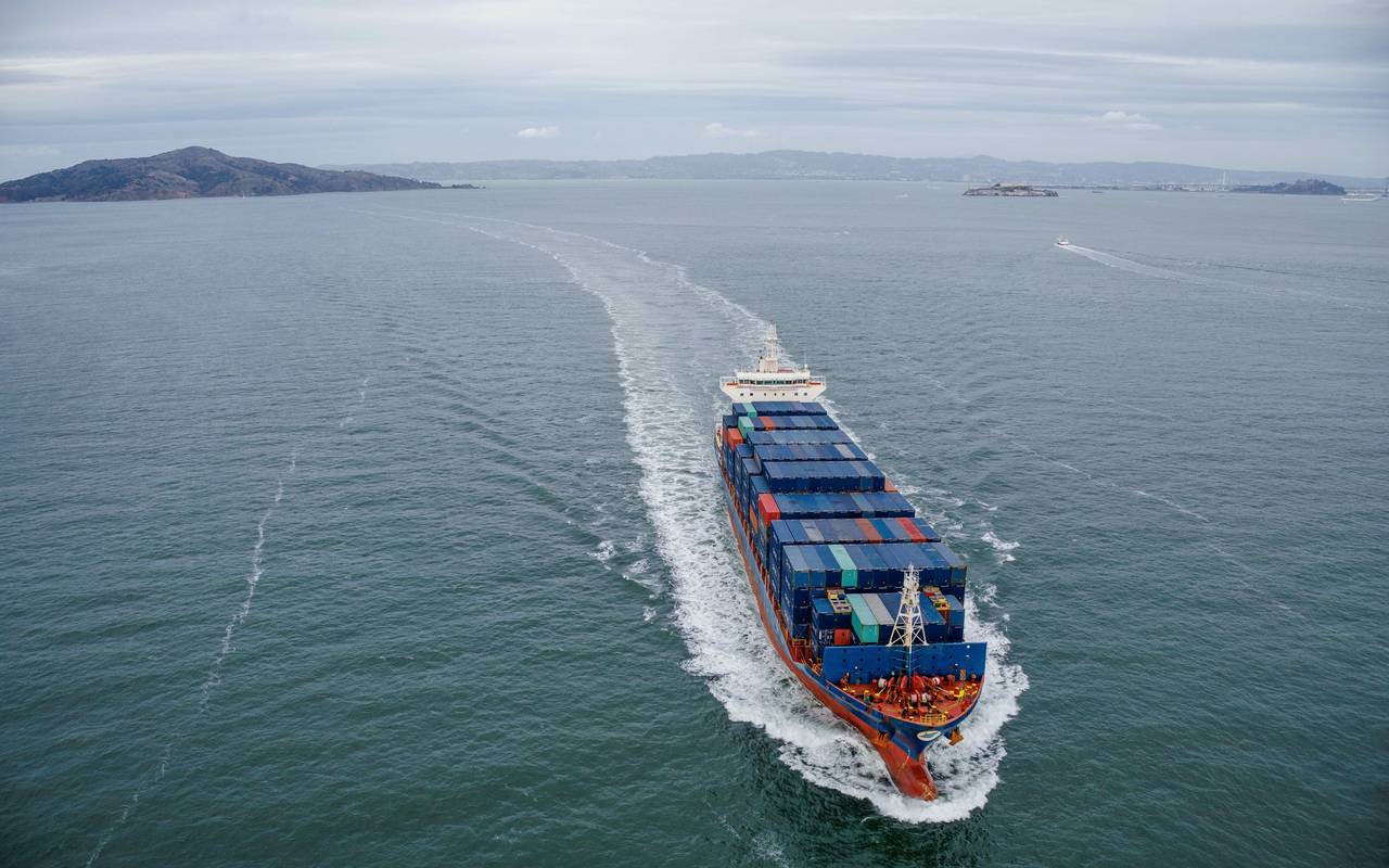 Aerial view of a large container ship sailing through open ocean waters.