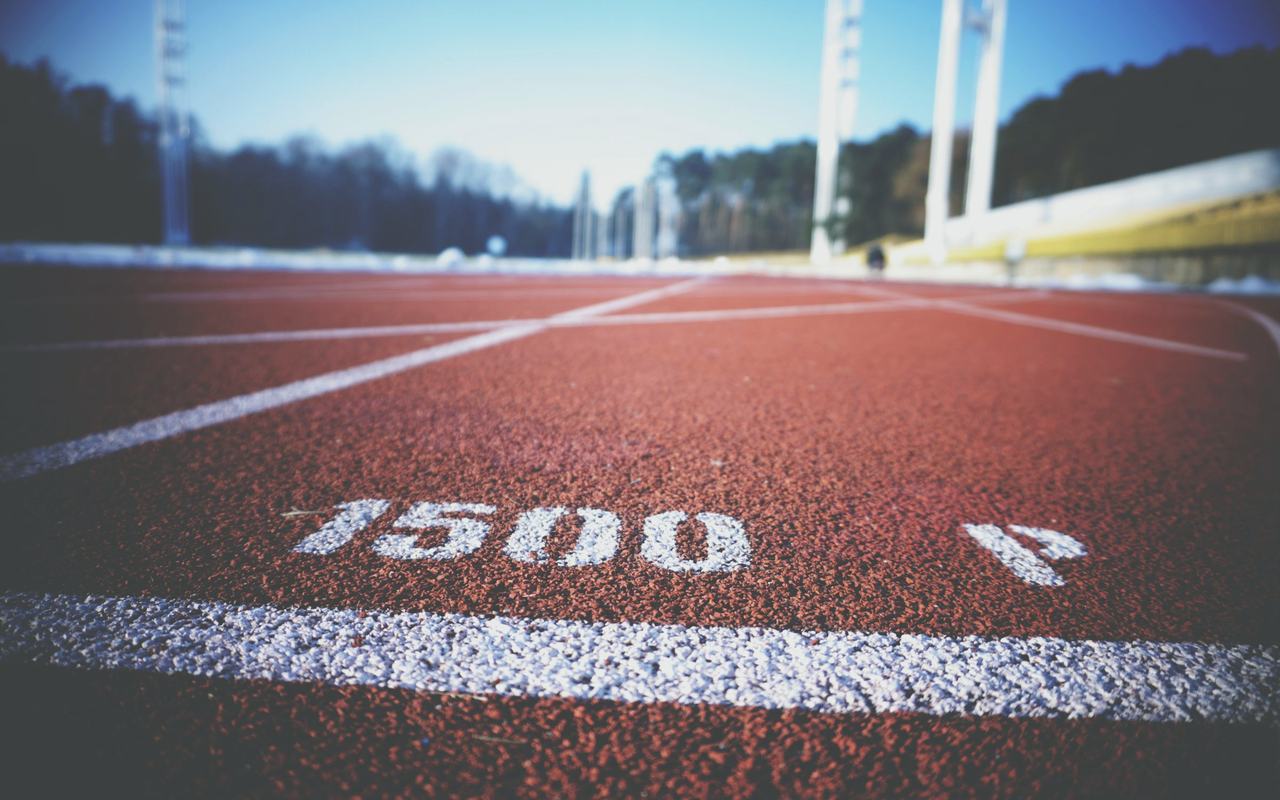 Empty running track lane with 1500 meter marking, sunny day outdoors.